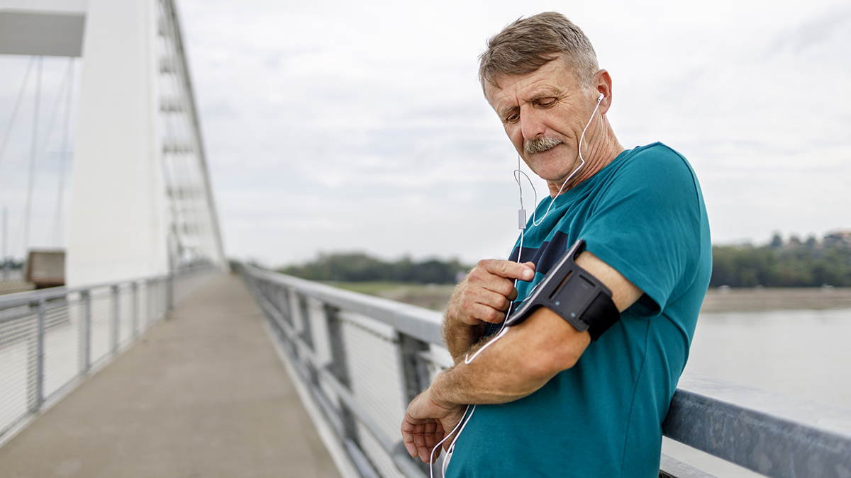 Older runners, one with a smartphone, tying shoelaces.