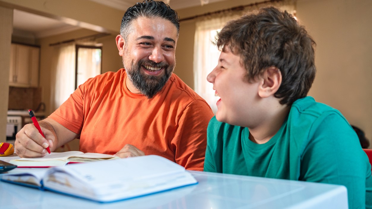 — title missing — Father and son at a table with an open notebook.