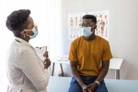 Reasons to vaccinate 1 Un hombre jóven escucha a un proveedor de atención médica en una clínica.